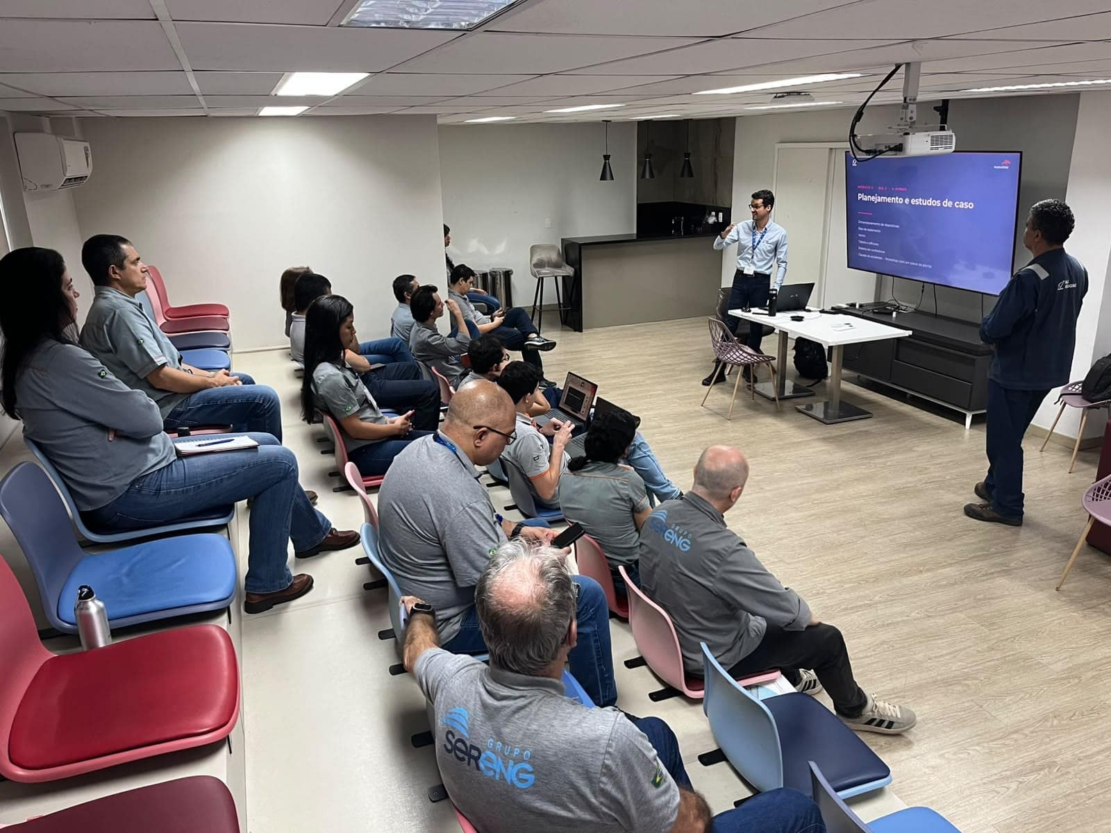 Instructor presenting on screen during a classroom technical training session, with participants seated